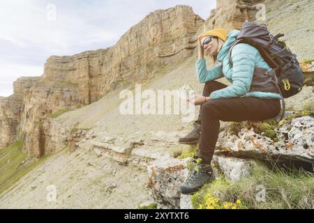 Une fille voyageuse portant un chapeau et des lunettes de soleil tient des billets de cent dollars dans les mains d'un fan sur fond de falaises sur la nature. Gardez votre HE Banque D'Images