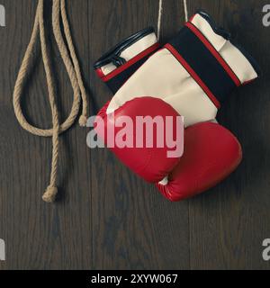 Gants de boxe rouge avec une corde à sauter sur un fond de bois Banque D'Images