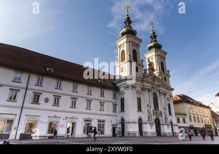 Autriche, 20.01.2019 : vue à l'église Mariahilf deux tours et place dans le centre-ville près de la rivière mur, soleil d'hiver destination voyage, Europe Banque D'Images