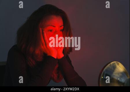 Jeune femme à la lumière d'une lampe témoin rouge Banque D'Images