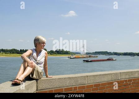 Femme assise sur un mur sur les rives du Rhin Banque D'Images