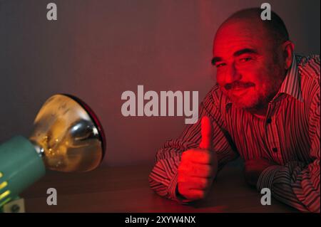 Homme avec les pouces vers le haut devant une lampe rouge Banque D'Images