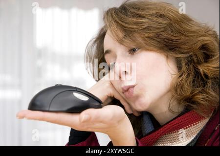 Jeune femme tenant une souris d'ordinateur devant son visage Banque D'Images