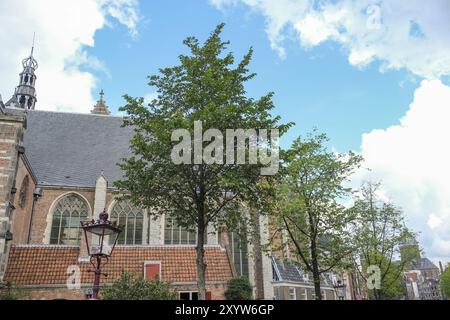 Arbres devant une église avec des murs de briques et de grandes fenêtres sous un ciel nuageux, Amsterdam, pays-Bas Banque D'Images