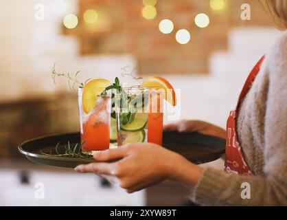 Young pretty woman with red and green cocktails on tray in the bar Stock Photo