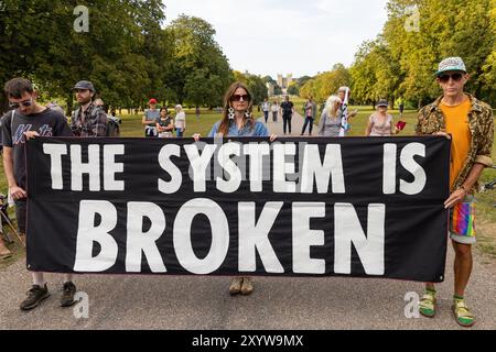 Windsor, Royaume-Uni. 30 août 2024. Les activistes climatiques de extinction Rebellion organisent une manifestation « le système est brisé » lors de la longue marche devant le château de Windsor, le premier des trois jours des activités de Upgrade Democracy. La campagne Upgrade Democracy d'extinction Rebellion vise à mettre en évidence la manière dont les profits sont sauvegardés pour les compagnies pétrolières et gazières au Royaume-Uni et à appeler le gouvernement britannique à créer et à être dirigé par une Assemblée de citoyens sur le climat et la justice écologique. Crédit : Mark Kerrison/Alamy Live News Banque D'Images