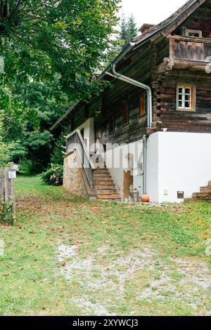 Un chalet en bois pittoresque se niche dans le paysage luxuriant, avec un escalier en pierre qui invite les visiteurs à explorer son entrée accueillante au milieu de Fallen Banque D'Images