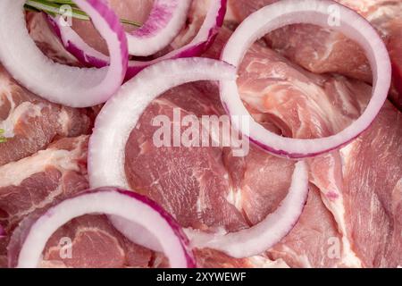 un morceau de viande de porc tranché du cou avec oignon rouge, viande de porc molle sur une planche à découper tout en marinant dans les oignons et les épices Banque D'Images