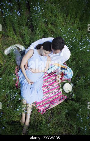 Young happy pregnant couple dans champ de lin Banque D'Images