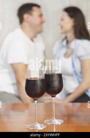 Jeune couple heureux appréciant un verre de vin rouge. Concentrez-vous sur les lunettes Banque D'Images