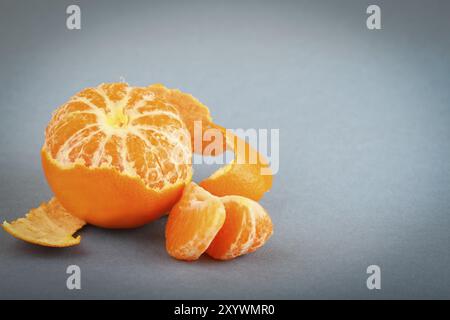 La mandarine avec pelé sur le gris Banque D'Images