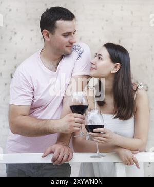 Jeune couple heureux dégustant un verre de vin rouge sur la terrasse Banque D'Images