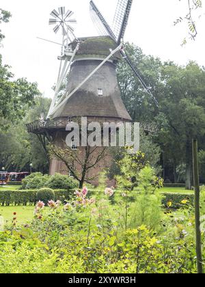 Grand moulin à vent au milieu d'un jardin bien entretenu avec des fleurs en fleurs et des arbres verts, Bad Zwischenahn, ammerland, allemagne Banque D'Images