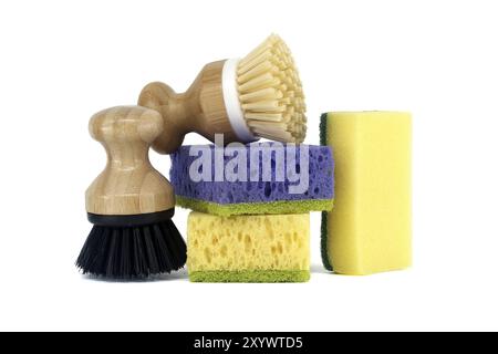 Trois éponges, chacune d'une couleur différente violet, jaune et bleu et deux brosses avec des poignées en bois isolées sur fond blanc, outils de nettoyage Banque D'Images