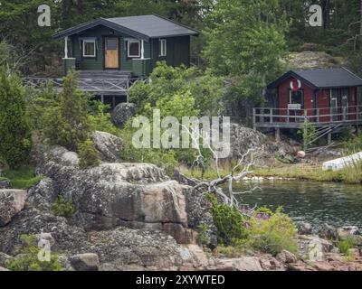 Deux maisons rustiques en bois se dressent sur des rochers sur le bord du lac, entouré par la forêt et l'eau, stockholm, mer baltique, suède, scandinavie Banque D'Images