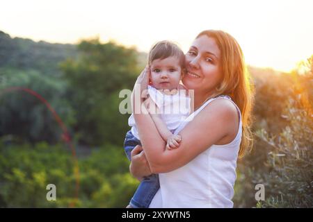 Jeune femme béatiful avec bébé à l'extérieur. Vacances en famille Banque D'Images