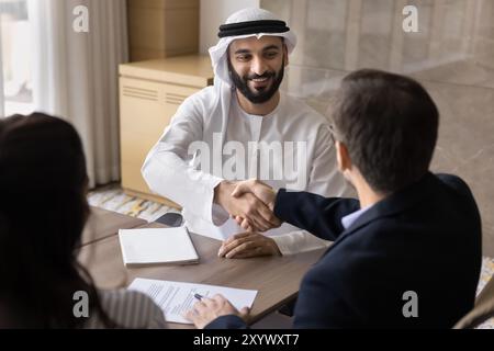 Heureux propriétaire d'une entreprise arabe confiante serrant la main à des collègues européens Banque D'Images