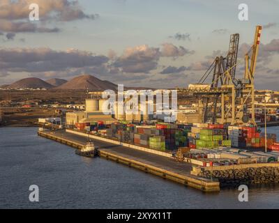 Port avec conteneurs et grues sur l'eau au coucher du soleil, montagnes et bâtiments industriels en arrière-plan, lanzarote, îles Canaries, Espagne, EUR Banque D'Images