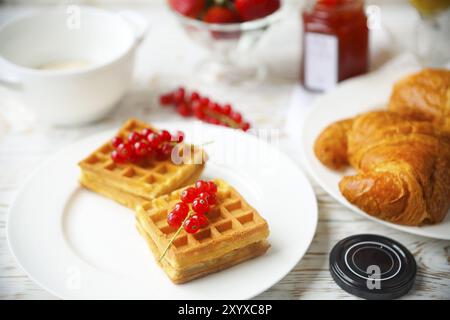 Gaufres aux fruits et de la confiture de groseille rouge sur une assiette blanche, croissants, jus d'orange et de flocons d'avoine Gruau sur le fond en bois Banque D'Images