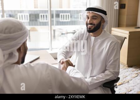 Joyeux jeune homme d'affaires arabe serrant la main à l'investisseur Banque D'Images