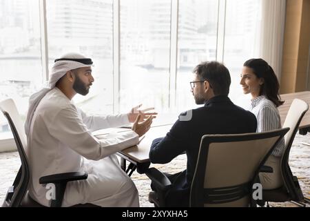 Jeune homme d'affaires arabe prospère parlant à des partenaires européens Banque D'Images
