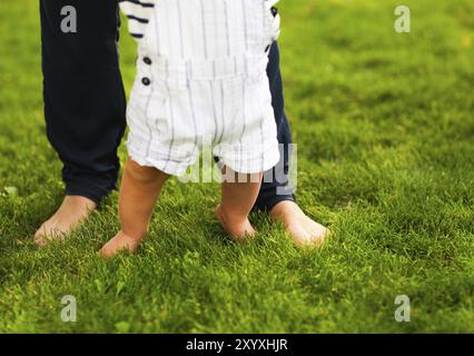 Bébé garçon Premiers pas et aider la mère dans son jardin d'été Banque D'Images