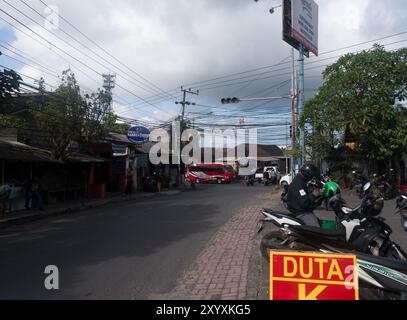 Scène de rue urbaine à Bali, Indonésie avec des motos, des magasins locaux et divers panneaux. Banque D'Images