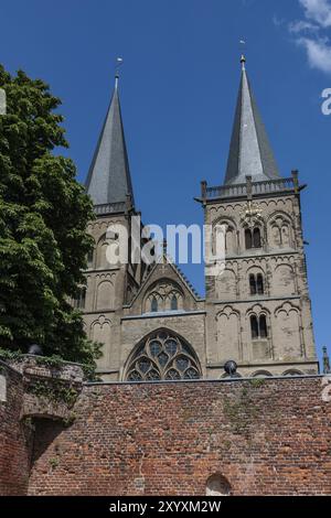 Église historique avec de hautes tours derrière un mur de briques et des arbres sous un ciel dégagé, Xanten, Bas Rhin, Rhénanie du Nord-Westphalie, Allemagne, Europe Banque D'Images