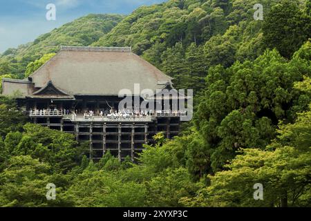 Vue lointaine du temple Kiyomizu-dera niché dans une forêt verte bondée de foules de visiteurs touristiques par un jour de ciel bleu clair à Kyoto, Japon, Asie Banque D'Images