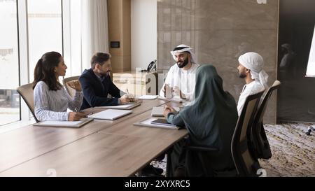 Heureux jeune homme d'affaires arabe parlant à divers partenaires Banque D'Images