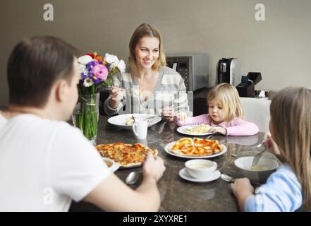 Famille heureuse dans la cuisine en train de dîner et de rire Banque D'Images