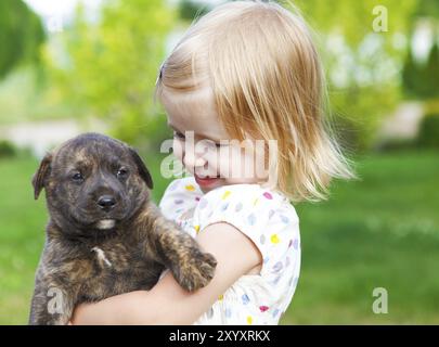 Cute little girl hugging dog puppy. L'amitié et de concept de soins Banque D'Images