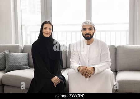 Beau mari arabe barbu et femme assis sur un canapé confortable Banque D'Images