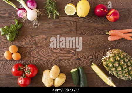 Un assortiment de fruits et légumes crus sur un fond de bois Banque D'Images