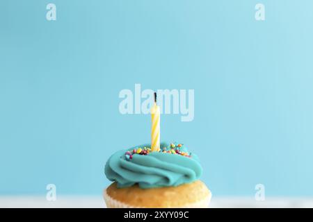 Concept de voeux d'anniversaire. Bougie soufflée sur un muffin ou un cupcake. Fond bleu Banque D'Images