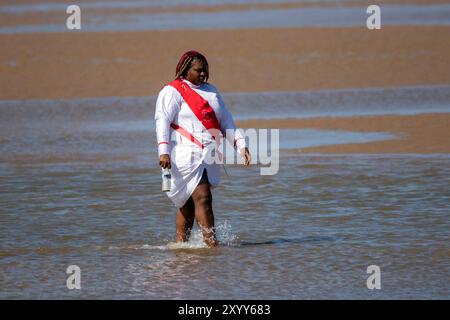 Jesus White Robe Biblical Red Sash ; Christian Group baignant dans la mer à Southport, Royaume-Uni Banque D'Images