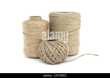 Trois bobines de ficelle de jute isolées sur fond blanc, chacune variant en taille, fabriquées à partir de matériaux naturels de jute Banque D'Images