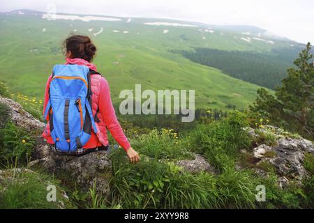 Hiker with backpack se détendre au sommet d'une montagne et profiter de la vallée durant le lever du soleil Banque D'Images