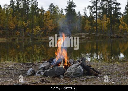 Feu de camp en suède sur un lac en automne Banque D'Images