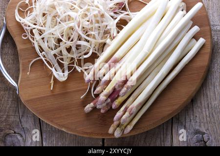 Asperges pelées et ingrédients pour une sauce sur planche de bois Banque D'Images