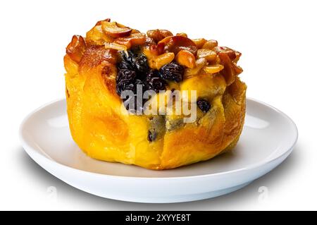 Pain au beurre garni de raisins secs et de noix dans un plat en céramique blanc isolé sur fond blanc avec chemin de découpage. Banque D'Images