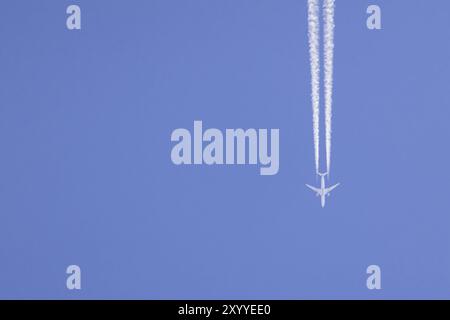 Airbus Airways du Qatar volant à travers un ciel bleu avec une traînée de vapeur ou traînée derrière, Angleterre, Royaume-Uni, Europe Banque D'Images