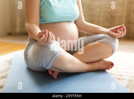 Close up of pregnant woman meditating while sitting in lotus position Banque D'Images