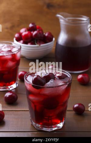 Gros plan de jus frais avec des cerises douces et de la glace sur fond en bois Banque D'Images