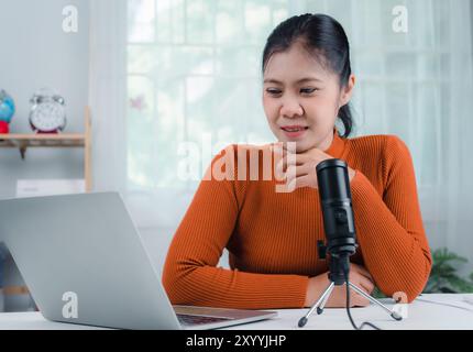 Concept de créateur de contenu, femme parlant dans le microphone sur le stand, diriger la communication en ligne, discuter du sujet, regarde l'écran d'ordinateur portable, engagé dans Strea Banque D'Images