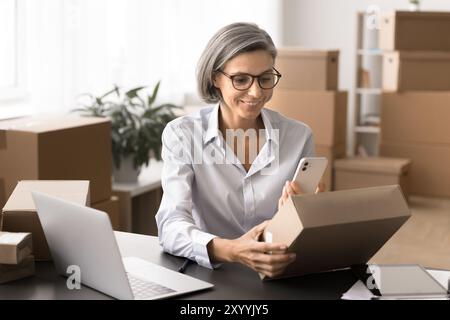 Travailleur tenant le téléphone portable scannant le code QR du paquet de vente au détail Banque D'Images