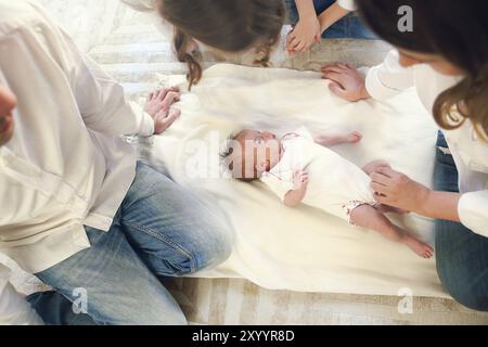 Grande famille avec trois enfants dans le salon blanc. Parents et enfants piquant par bébé nouveau-né. Mère, père et enfants jouant avec le chil nouveau-né Banque D'Images