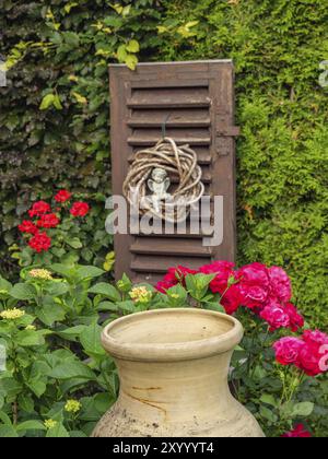 Grand vase en céramique dans un jardin fleuri avec fleurs rouges et décoration, borken, muensterland, allemagne Banque D'Images