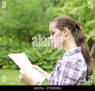 Jeune fille brune dans la campagne tenant une carte Banque D'Images