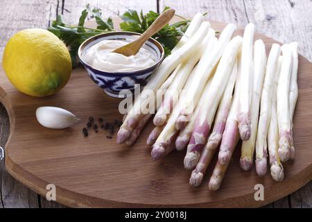 Asperges pelées et ingrédients pour une sauce sur planche de bois Banque D'Images